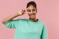 Smiling young african american woman girl in green sweatshirt posing isolated on pastel pink background studio portrait Royalty Free Stock Photo