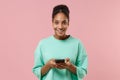 Smiling young african american woman girl in green sweatshirt posing isolated on pastel pink background in studio Royalty Free Stock Photo