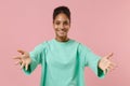 Smiling young african american woman girl in green sweatshirt posing isolated on pastel pink wall background. People Royalty Free Stock Photo