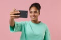 Smiling young african american woman girl in green sweatshirt posing isolated on pastel pink wall background in studio Royalty Free Stock Photo