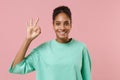 Smiling young african american woman girl in green sweatshirt posing isolated on pastel pink wall background studio Royalty Free Stock Photo