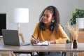 Smiling young African American woman in headphones distracted from computer work look in distance dreaming. Happy biracial female Royalty Free Stock Photo