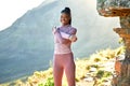 Smiling young african american woman hiking on a trail, stretching her arms and shoulder. Portrait of a smiling young