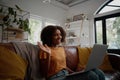 Smiling young african american woman relaxing on the couch waving hand while talking to friends on a video call at home