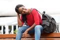 Smiling young african american woman sitting on bench in the city with bag Royalty Free Stock Photo