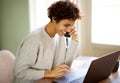 Smiling young african american woman talking on mobile phone and looking at laptop computer Royalty Free Stock Photo