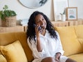 Smiling young african american woman talking on the phone sitting on the sofa Royalty Free Stock Photo