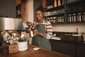 Smiling young African barista frothing milk behind a cafe counter