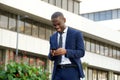 Smiling young african businessman walking with smart phone in city Royalty Free Stock Photo
