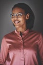 Smiling young African businesswoman standing against a gray back