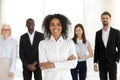 Smiling african employee standing with diverse team in office, p