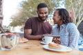 Smiling African couple browsing online at a sidewalk cafe table Royalty Free Stock Photo