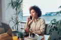 Young African female entrepreneur sitting at a desk in her home office working online with a laptop Royalty Free Stock Photo