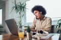 Young African female entrepreneur sitting at a desk in her home office working online with a laptop Royalty Free Stock Photo