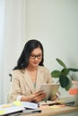 Smiling young African female entrepreneur working online with a digital tablet while sitting at a table in her home office Royalty Free Stock Photo