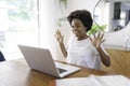 Smiling young African female entrepreneur working online with a laptop while sitting at her kitchen table at home Royalty Free Stock Photo