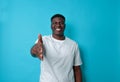 Smiling young African guy holds out his hand in a handshake on a blue background. Royalty Free Stock Photo
