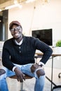 Smiling young African man sitting on chair at his modern office. Concept of happy business people Royalty Free Stock Photo