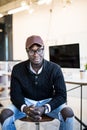 Smiling young African man sitting on chair at his modern office. Concept of happy business people Royalty Free Stock Photo