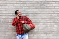 Smiling young african man talking on cellphone by wall Royalty Free Stock Photo