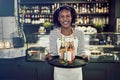 Smiling young African waitress holding a tray of drinks