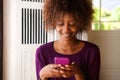 Smiling young african woman looking at cell phone Royalty Free Stock Photo