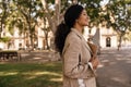 Smiling young african woman looks away spends time in square holds documents and folders. Royalty Free Stock Photo