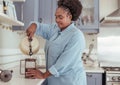 Smiling young African woman preparing fresh coffee in her kitchen