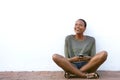 Smiling young african woman sitting on floor with mobile phone Royalty Free Stock Photo