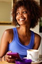 Smiling young african woman using cell phone at cafe Royalty Free Stock Photo