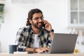 Smiling arab man freelancer talking on phone and taking notes Royalty Free Stock Photo