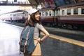 Smiling young Asian backpacker female standing at train station. Summer travel lifestyle concept