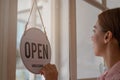 Smiling young asian business owner, employee retail,coffee shop woman,girl turning,setting sign board to open for welcome customer