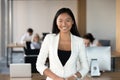 Smiling young asian business woman looking at camera in office