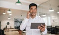 Smiling Asian businessman using a cellphone and tablet at work Royalty Free Stock Photo