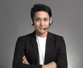 Smiling young asian businessman talking on headset against gray background Royalty Free Stock Photo