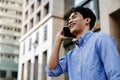 Smiling Young Asian Businessman Using Mobile Phone in Big Urban City Royalty Free Stock Photo