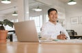 Smiling young Asian businessman working alone at his office desk Royalty Free Stock Photo