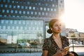 Smiling Asian businesswoman listening to music at a bus stop Royalty Free Stock Photo