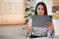 Smiling Asian businesswoman using her tablet to manage her business tasks at her desk Royalty Free Stock Photo