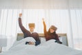 Smiling young asian couple sitting on white bed and playing game using virtual reality headset