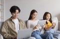 Smiling young asian couple and teen girl chatting on gadgets, playing online, surfing in internet Royalty Free Stock Photo