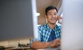 Smiling Asian designer working at his desk in an office Royalty Free Stock Photo