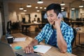 Smiling Asian designer talking on a cellphone and working online Royalty Free Stock Photo