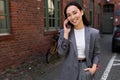 Smiling Asian business woman talking on mobile phone standing outside. Royalty Free Stock Photo