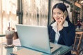 Smiling young asian executive business woman using her cell phone and working on her computer Royalty Free Stock Photo