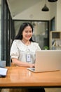 Smiling young Asian female secretary or office worker is working on her task on laptop Royalty Free Stock Photo