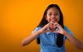 Smiling young asian girl in blue shirt showing heart shape with two hands Royalty Free Stock Photo