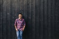 Smiling young Asian man leaning against a dark wall outside Royalty Free Stock Photo