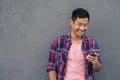 Smiling young Asian man reading a text on his cellphone Royalty Free Stock Photo
